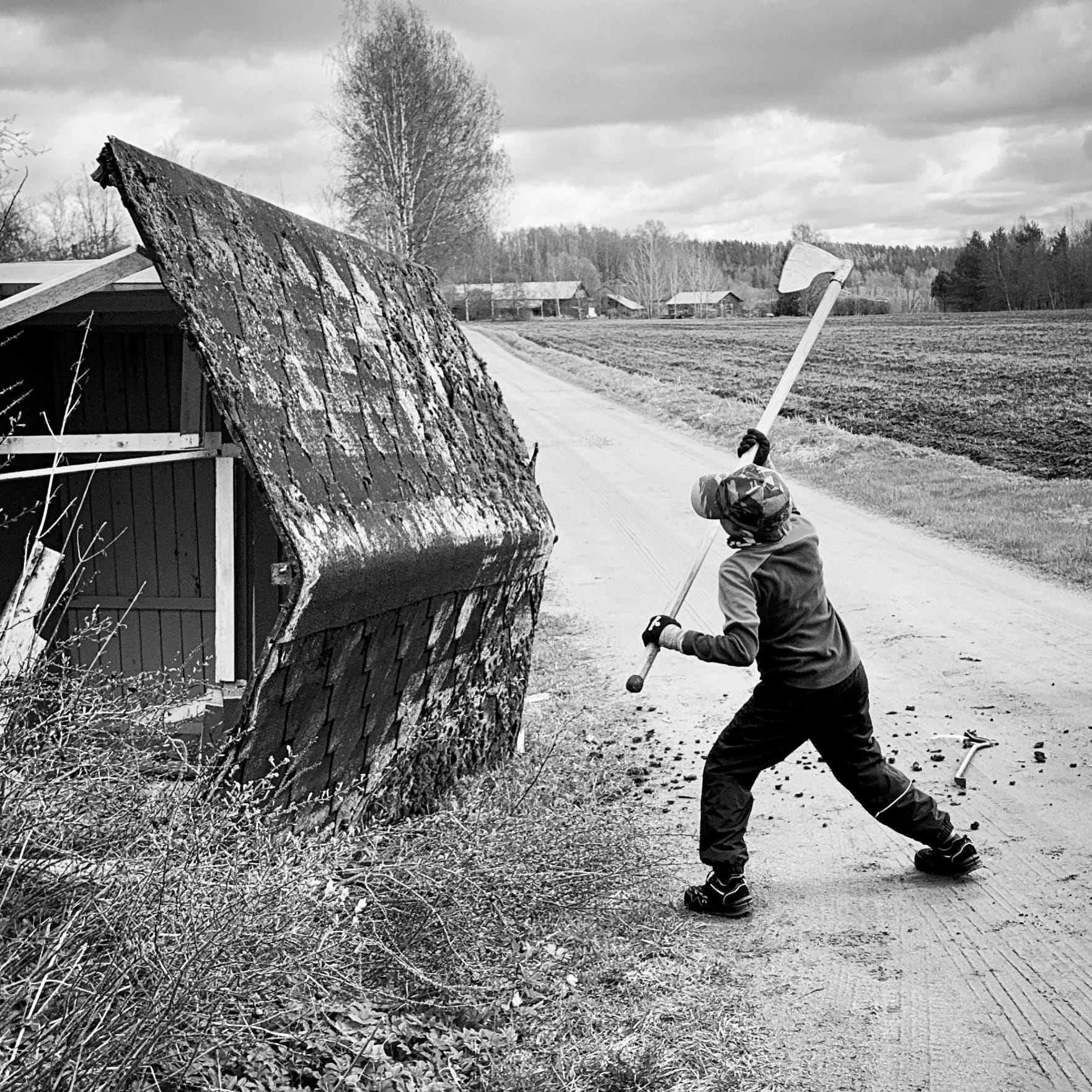 Nuori poika ison kirveen kanssa tuhoamassa leikkimökkiä.